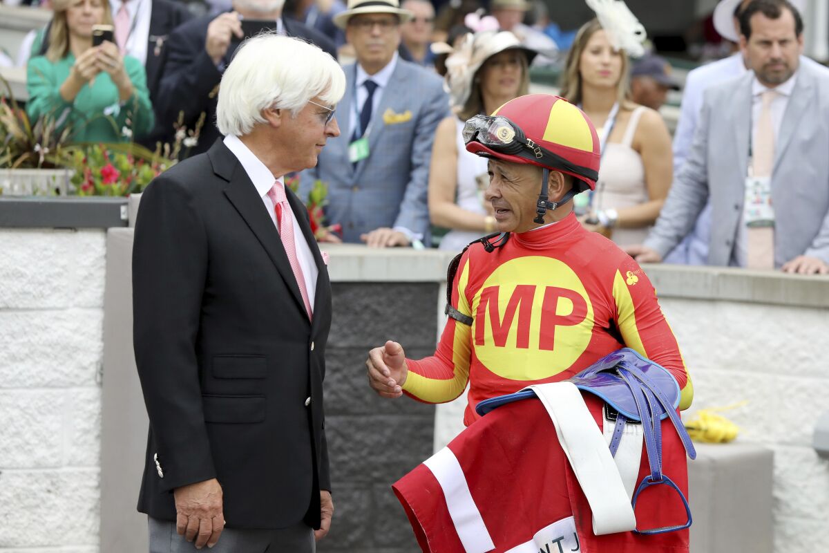 FILE - Jockey Mike Smith talks with trainer Bob Baffert after winning the Grade 2 Alysheba at Churchill Downs, Friday, May 3, 2019, in Louisville, Ky. The Kentucky Derby leads off the first Triple Crown season in decades without the chance of Bob Baffert officially winning one or more of the three races. Baffert's absence while suspended shadows over the race particularly because two horses he trained for a significant period of time are among the top contenders. (AP Photo/Gregory Payan, File)
