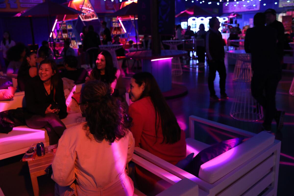 People seated in a dark room with pink lighting.