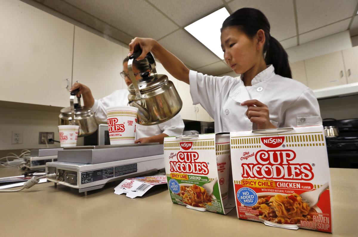 Nissin Foods USA research development assistants Veronica Sanchez, left, and Saori Seki prepare their company's noodle dishes in a Gardena test kitchen.