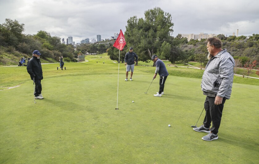 Golfers Tom Cudal, Manny Celedon, Nick Cudal, and Dan Martin putt on the 18th green at Balboa Park Golf Course 