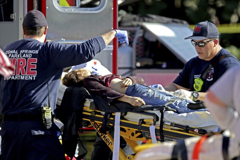 Medical personnel tend to a victim following a shooting at Marjory Stoneman Douglas High School in Parkland, Fla., on Wednesday, Feb. 14, 2018. (John McCall/South Florida Sun-Sentinel via AP)