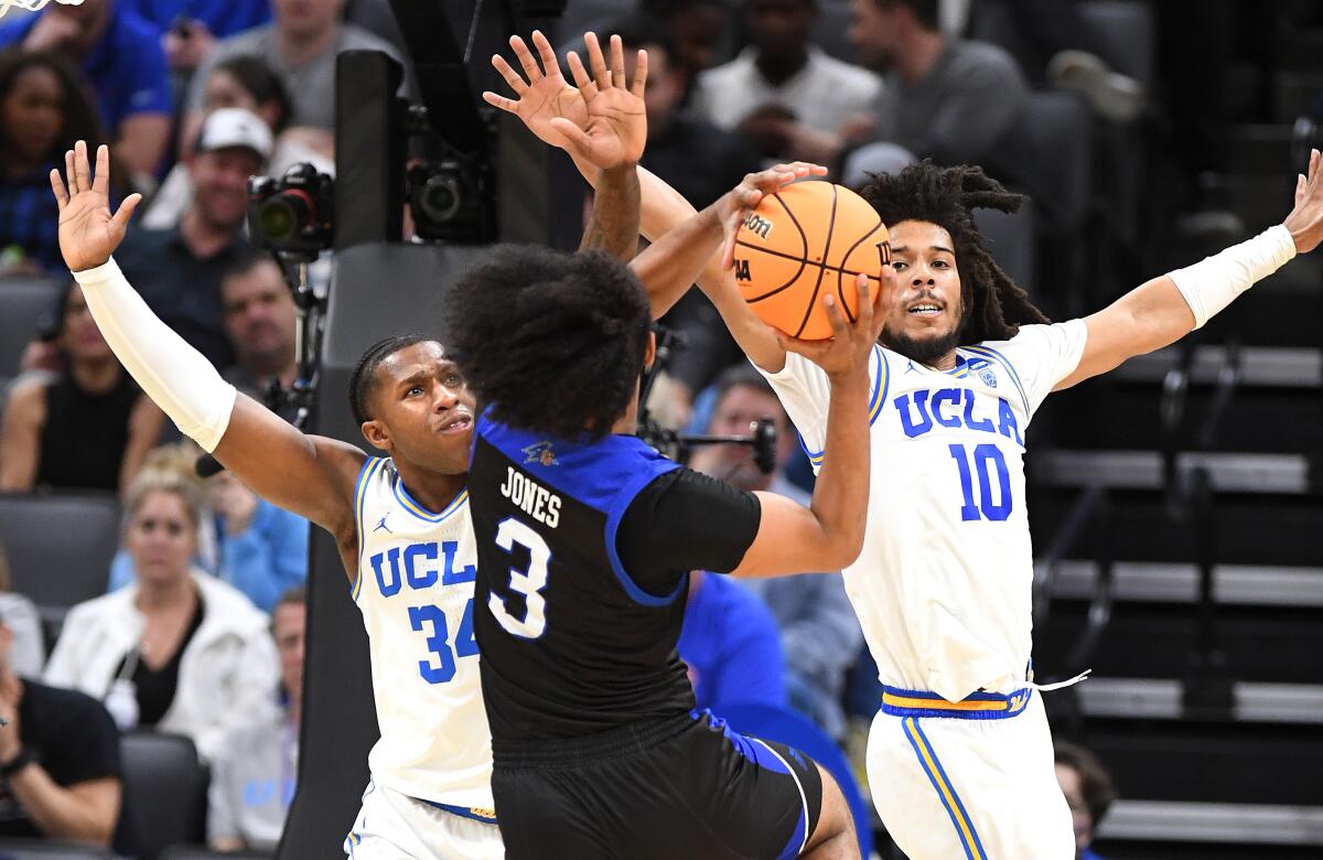 UCLA's David Singleton, left, and Tyger Campbell defend UNC Asheville's Tajion Jones in the NCAA tournament March 16, 2023.