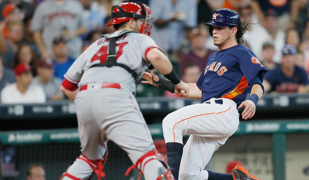 Colby Rasmus, right, of the Astros scores in the third inning as Angels catcher Jett Bandy awaits the throw Sunday.