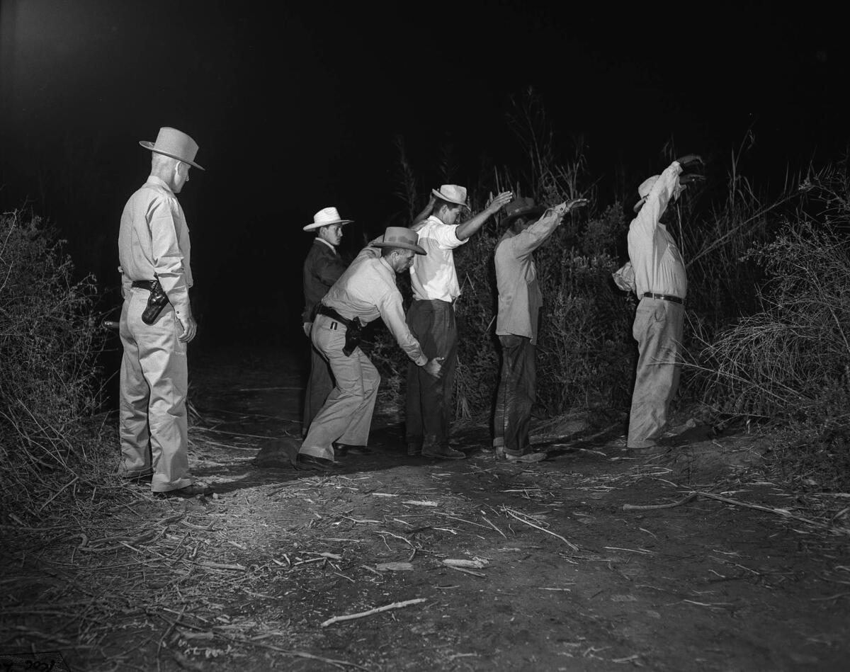 A Border Patrol officer searches four immigrants caught entering California illegally from Mexico. This photo appeared in the May 2, 1950, Los Angeles Times.