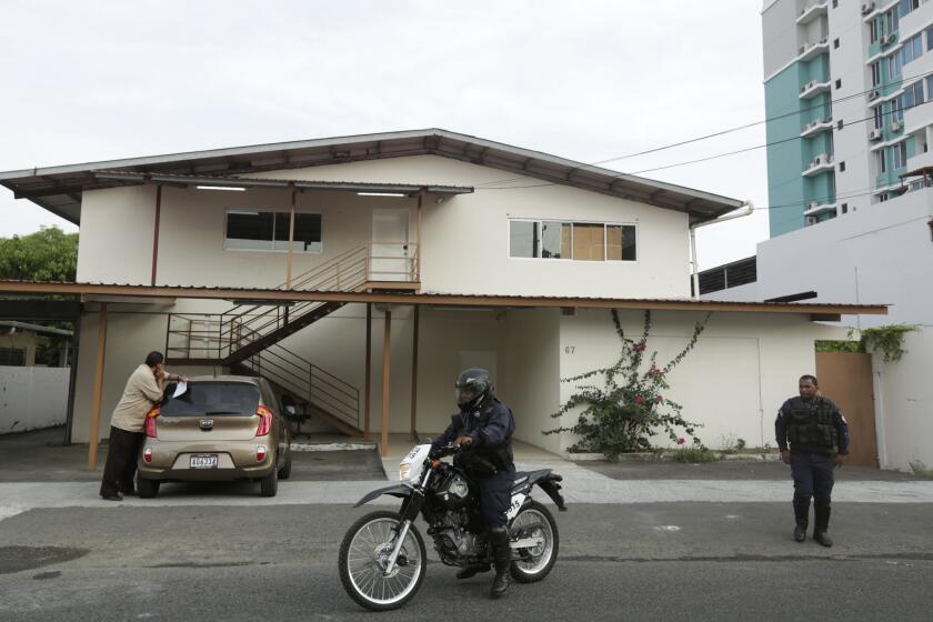 Panamanian police officers and a private security guard stand outside a warehouse used by the Mossack Fonseca law firm, that was raided by prosecutors, April 22 in Panama City, Panama.