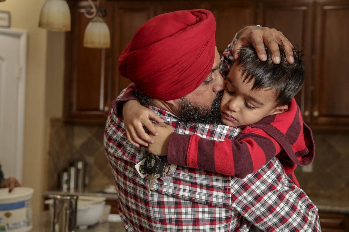 Singh comforts his 4-year-old son, Devjot Kamboj, who was saddened after finding out that his dad would leave for a cross-country delivery. (Irfan Khan / Los Angeles Times)