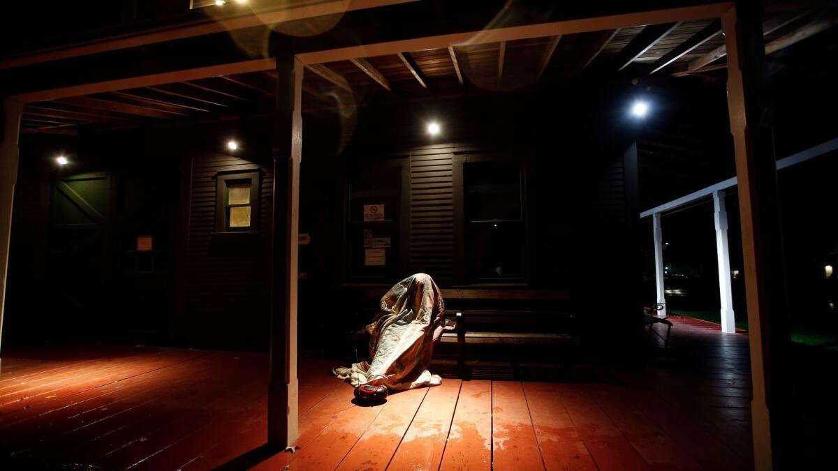 A homeless man sleeps on a porch, out of the rain, near L.A.'s Hollywood Bowl on January 11.