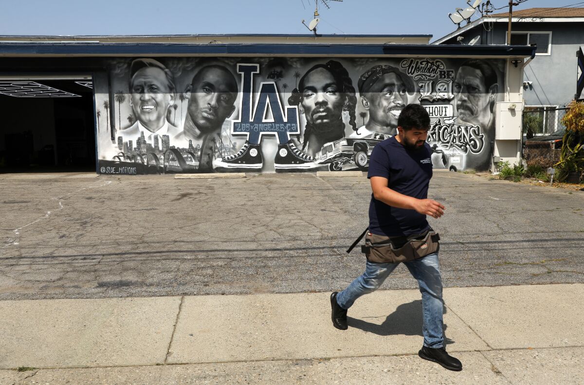 An employee of Speedy Auto Tint in Bellflower, California walks in front of the business and its mural.