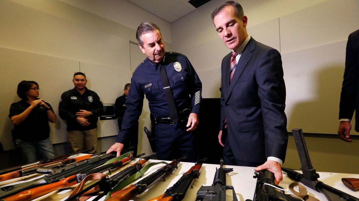 LAPD Chief Charlie Beck, left, and Mayor Eric Garcetti get a close look at some of the weapons collected at a recent gun buyback.