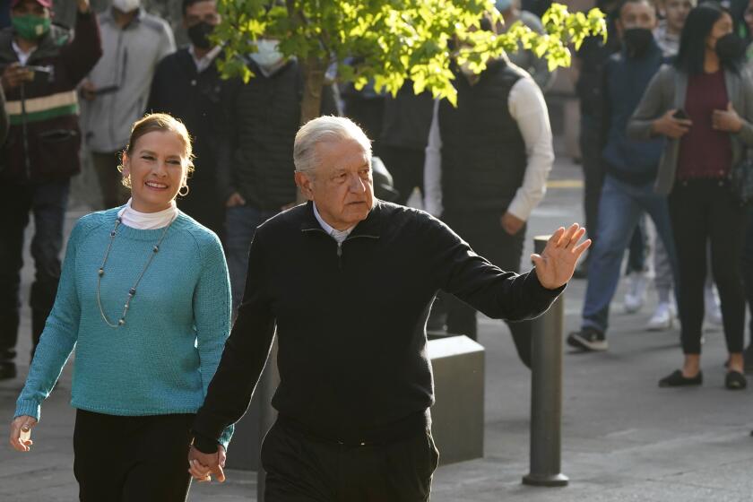 Mexico´s President Andres Manuel Lopez Obrador walks with his wife Beatriz Gutierrez Muller, before voting in a national referendum on whether he should end his six-year term barely midway through or continue to the end, outside their polling station in Mexico City, Sunday, April 10, 2022. (AP Photo/Eduardo Verdugo)