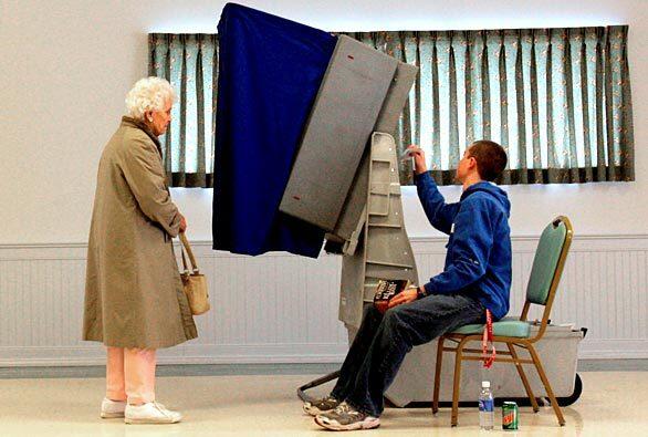 Poll worker Barett Smith, right, readies a voting machine Tuesday for Lois Scultz, 91, in Greenwood, Del.