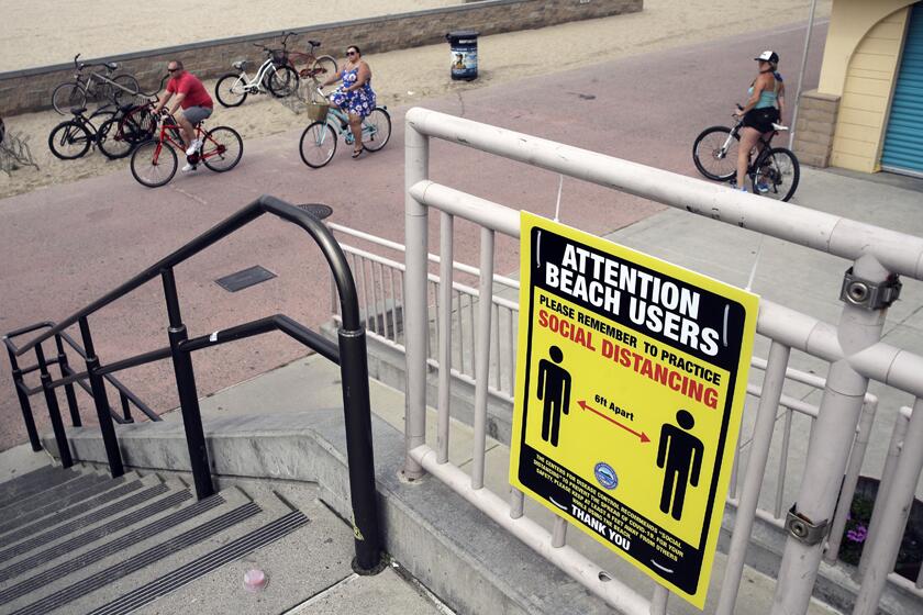 A sign in Huntington Beach encourages people to practice social distance.