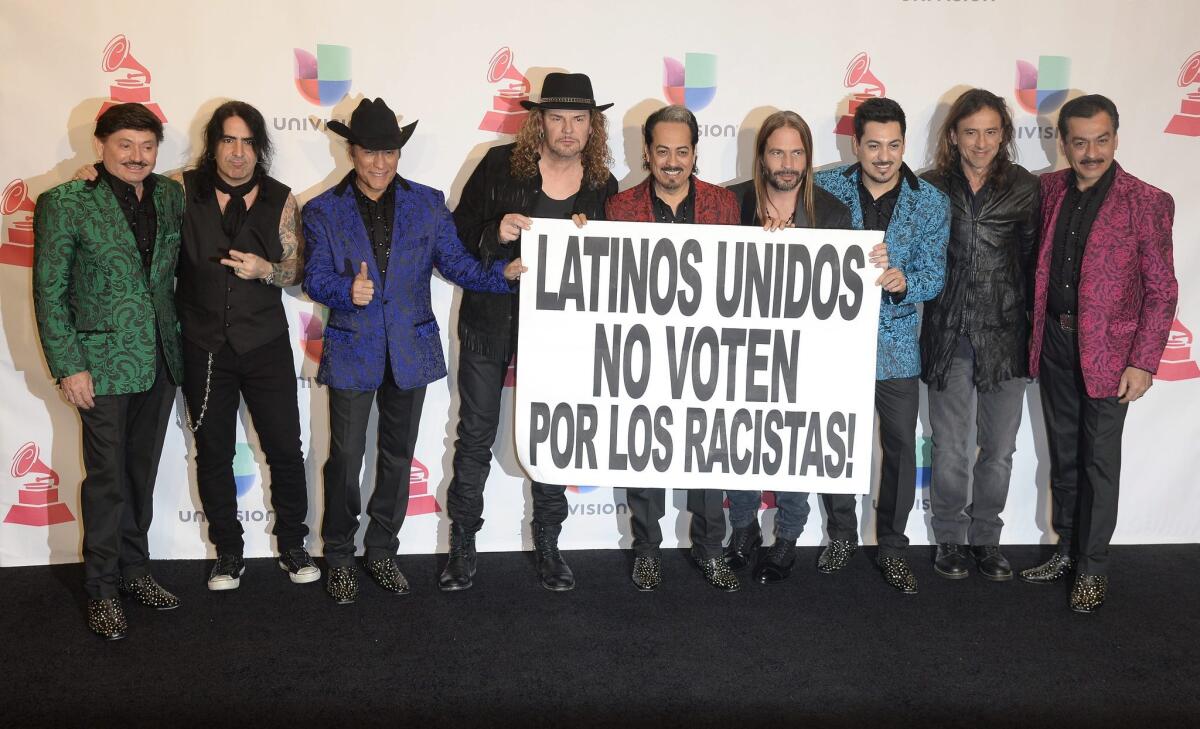 Mexican rock band Maná and norteño group Los Tigres Del Norte pose with the banner they held up during their performance at the Latin Grammy Awards: 'Latinos United, Don't Vote for Racists.'
