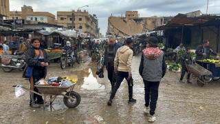 People with wheelbarrows and others shopping at an outdoor market