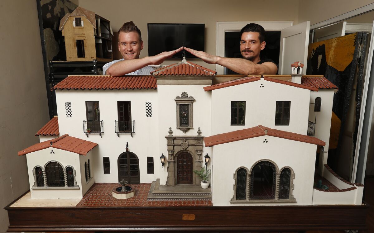 Matthew Mathiasen and his partner, artist Chris Toledo, with Toledo's latest piece, a 1920s Spanish Mediterranean miniature home that Toledo has spent the last two years building.