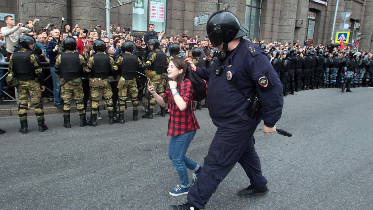 A Russian police officer detains a teenager in St. Petersburg during one of many protests against changes to retirement ages.