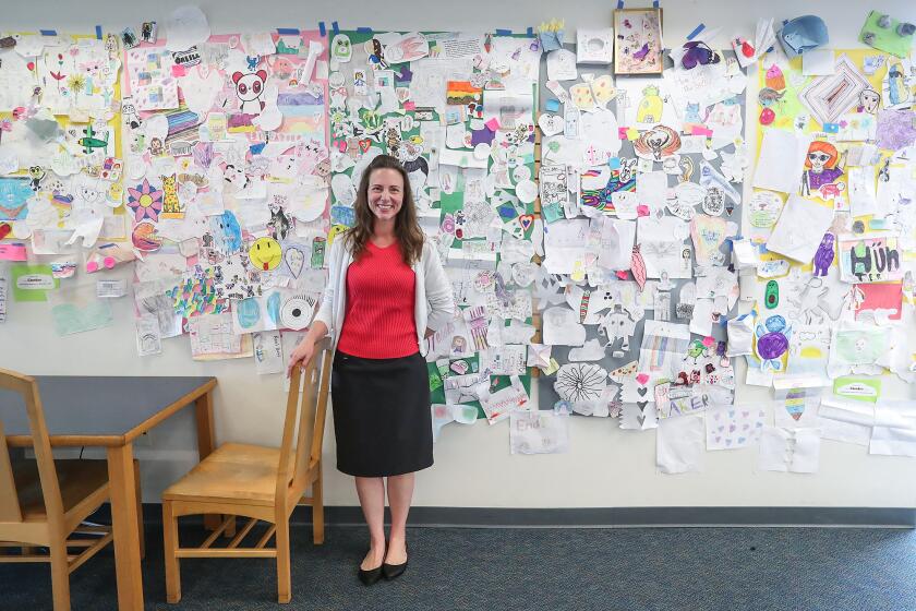 Library-Media tech Jacquelyn Casella stands with a few hundred of the Mariners Elementary Comicon art work on the school's library wall on Thursday.