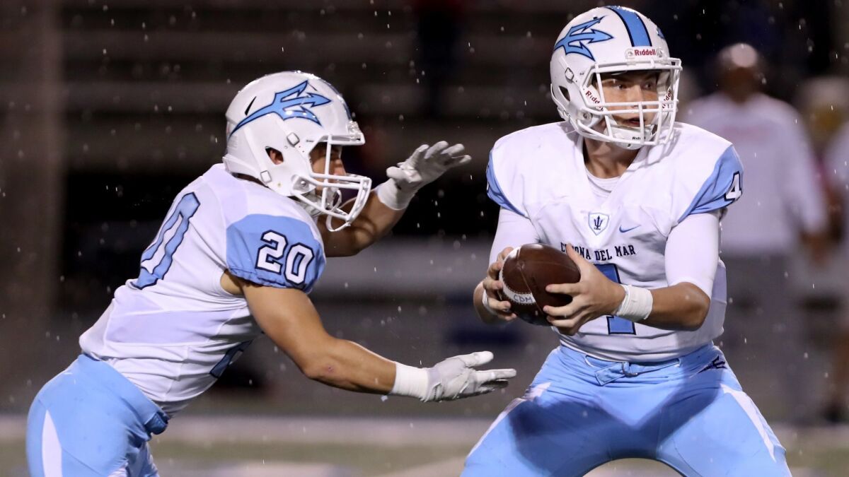 Corona del Mar High quarterback Ethan Garbers, right, hands off to running back Jason Vicencio during the Sea Kings' Sunset League game against Los Alamitos on Friday at Cerritos College. The game, halted due to lightning, will not be completed and ends as a 7-7 tie.