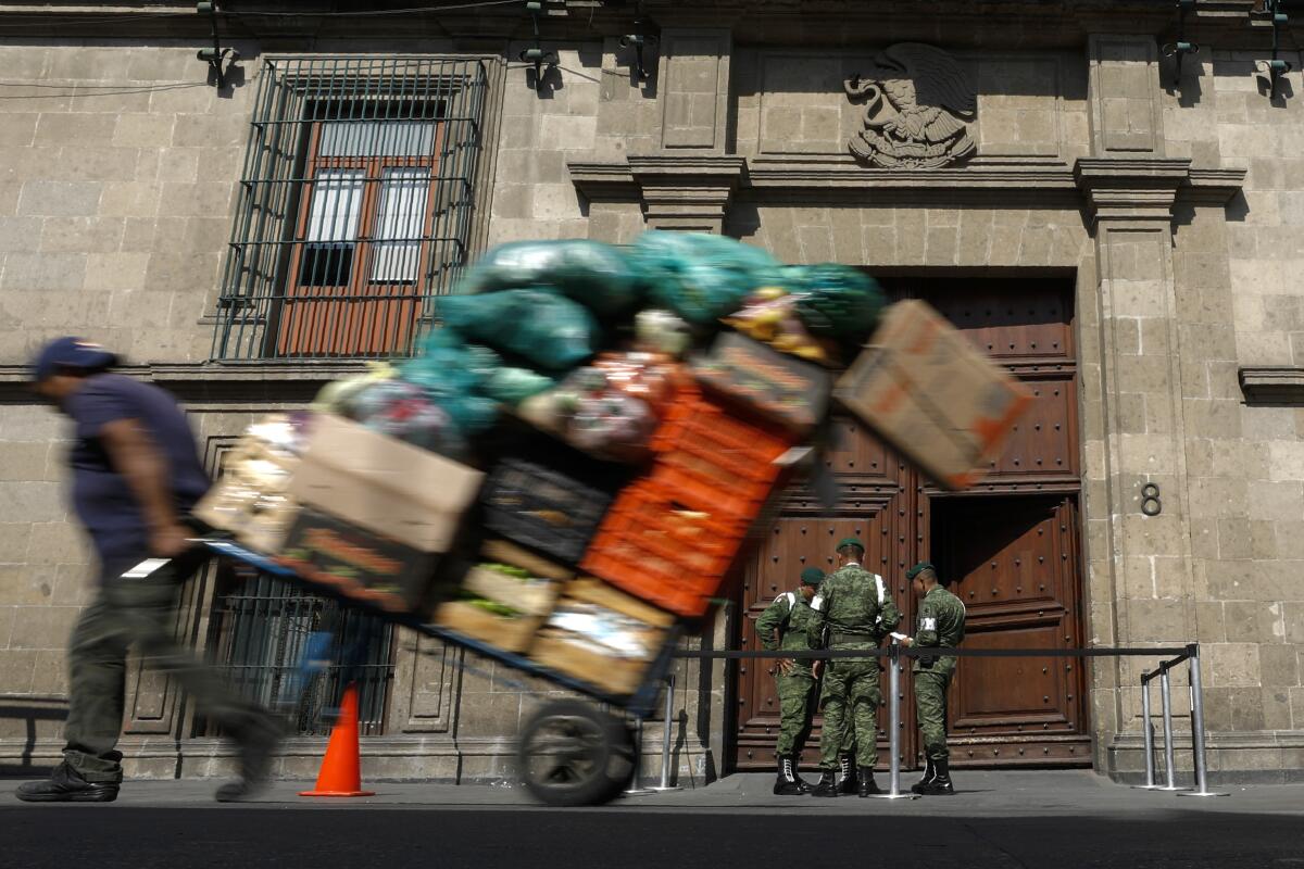 ARCHIVO - Un hombre pasa cargado con mercancía por delante del Palacio 
