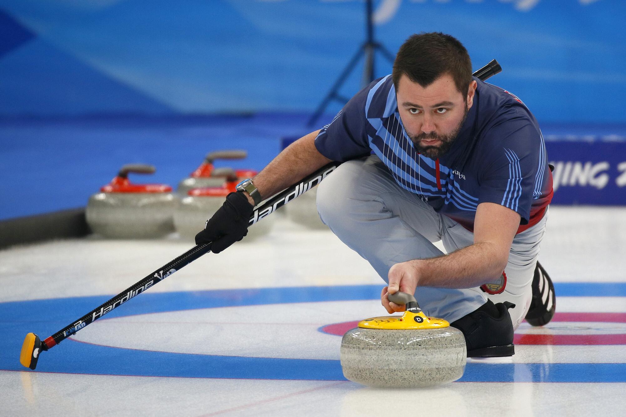A man prepares to release the curling stone.