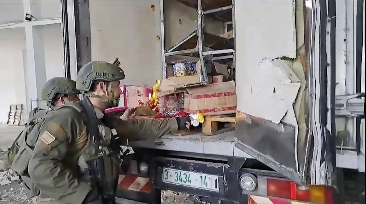 Soldiers hold lighters up to cardboard boxes in the back of a truck.