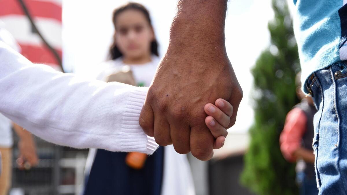 A man holds his daughter's hand after picking her and his wife up at a Guatemalan air force base on July 10, 2018. His wife and daughter had been deported from the United States.