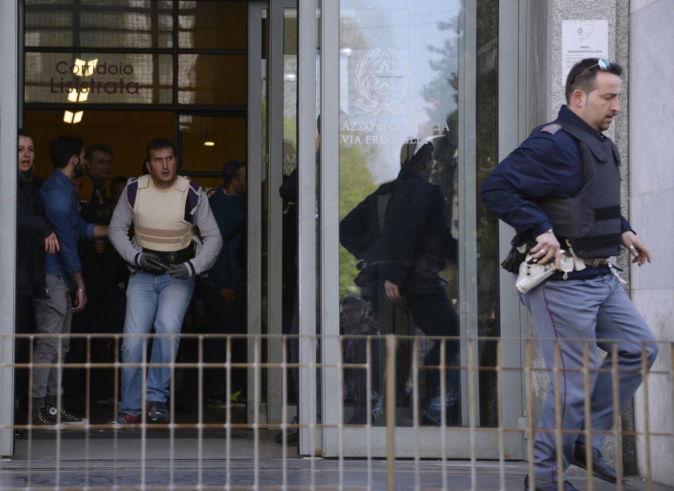 Police officers run through the entrance to Milan's courthouse during a shooting on April 9, 2015. An armed man, identified as Claudio Giardiello, believed to be a defendant in a bankruptcy case was apprehended as the gunman.