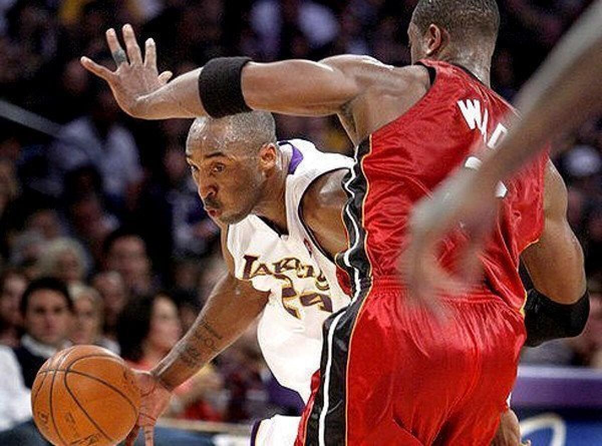 Lakers guard Kobe Bryant tries to drive his way around Heat guard Dwyane Wade.