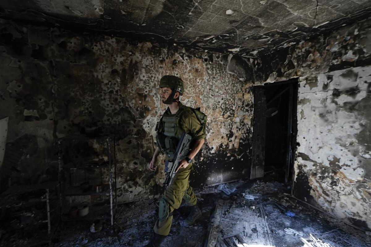 An Israeli soldier inspects a house damaged by Hamas militants in Kibbutz Kfar Azza, Israel, 