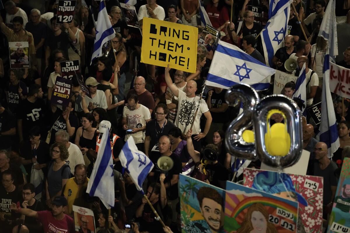 People protest holding Israeli flags and a sign that says "Bring them home!"