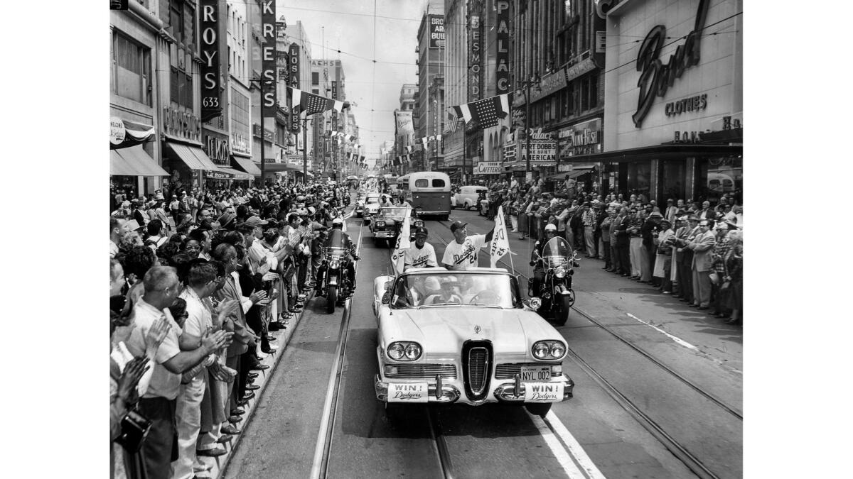 April 18, 1958: Spectators line Broadway as Dodgers manager Walter Alston, right, and coach Charlie Dressen ride to the first game at Memorial Coliseum.