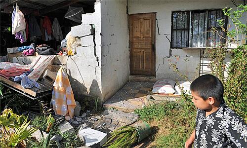 A child looks at a damaged house in Fraijanes, about 30 kilometers north of the capital and the origin of the 6.1-magnitude temblor.