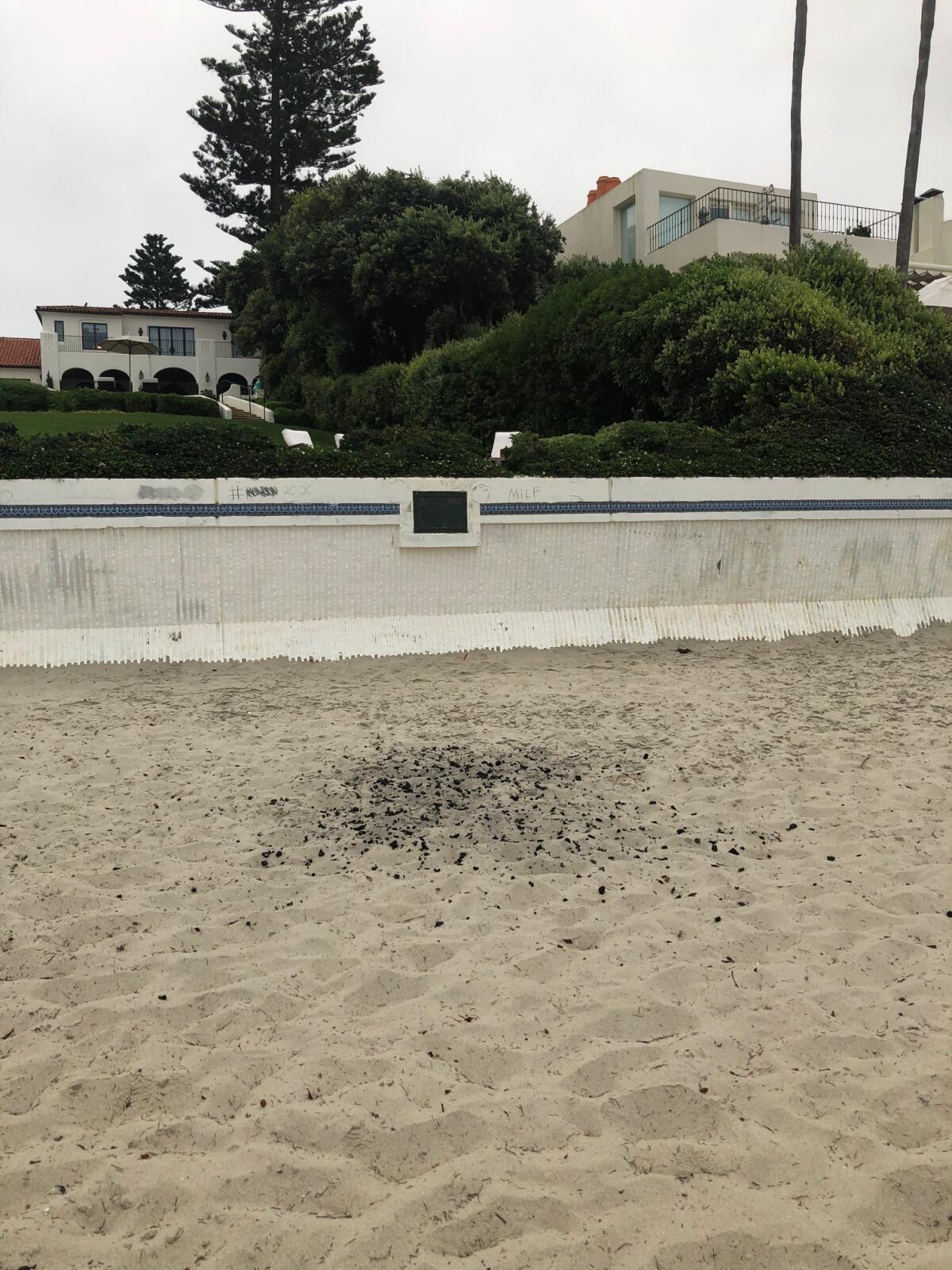 Remnants from a beach fire are scattered in the sand at Marine Street Beach in La Jolla.
