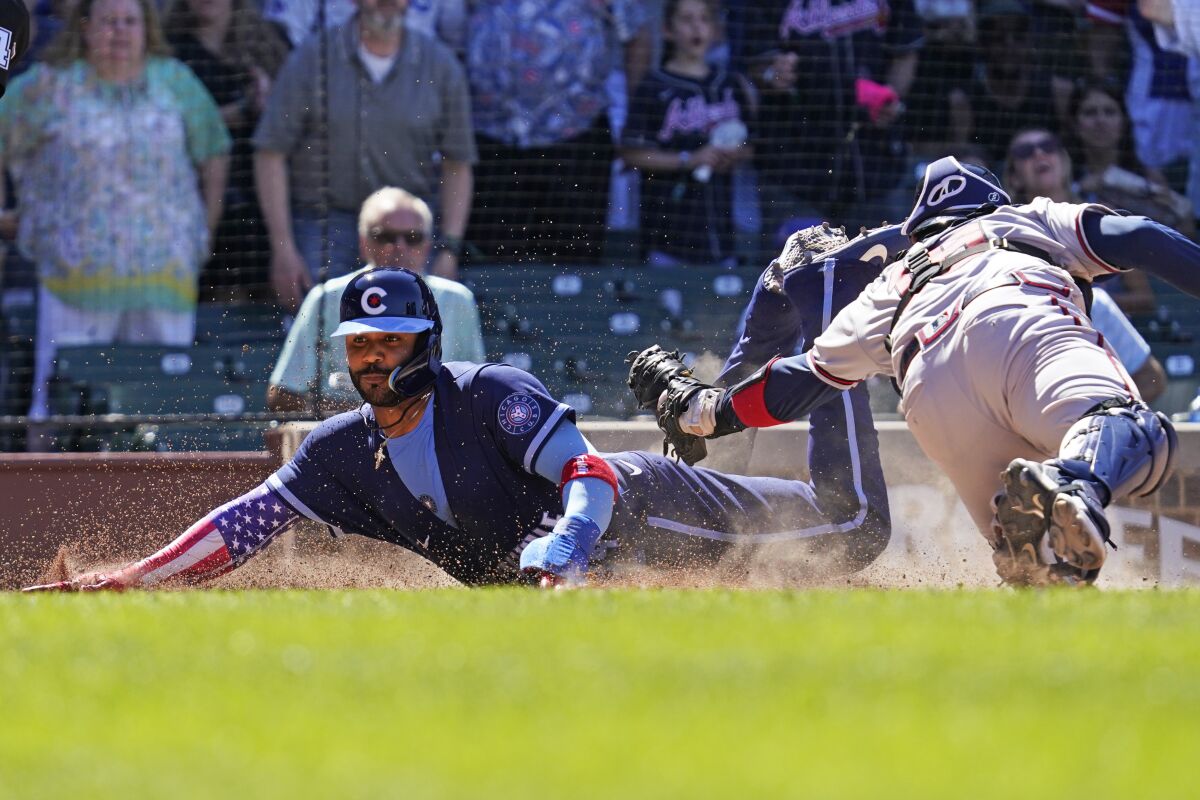 Chicago Cubs' Jonathan Villar, left, scores on a sacrifice fly by Christopher Morel as Atlanta Braves catcher Travis d'Arnaud applies a late tag during the eighth inning of a baseball game in Chicago, Friday, June 17, 2022. (AP Photo/Nam Y. Huh)
