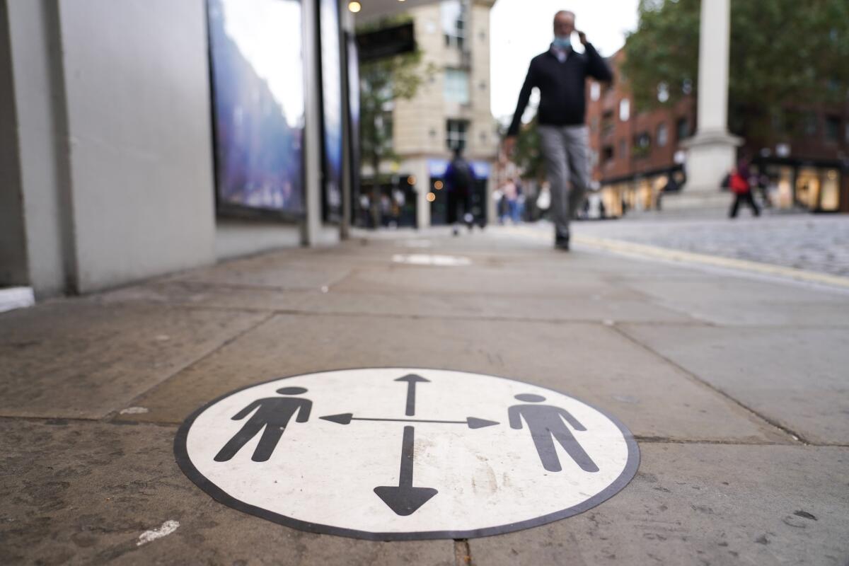 A sidewalk sign promotes social distancing.