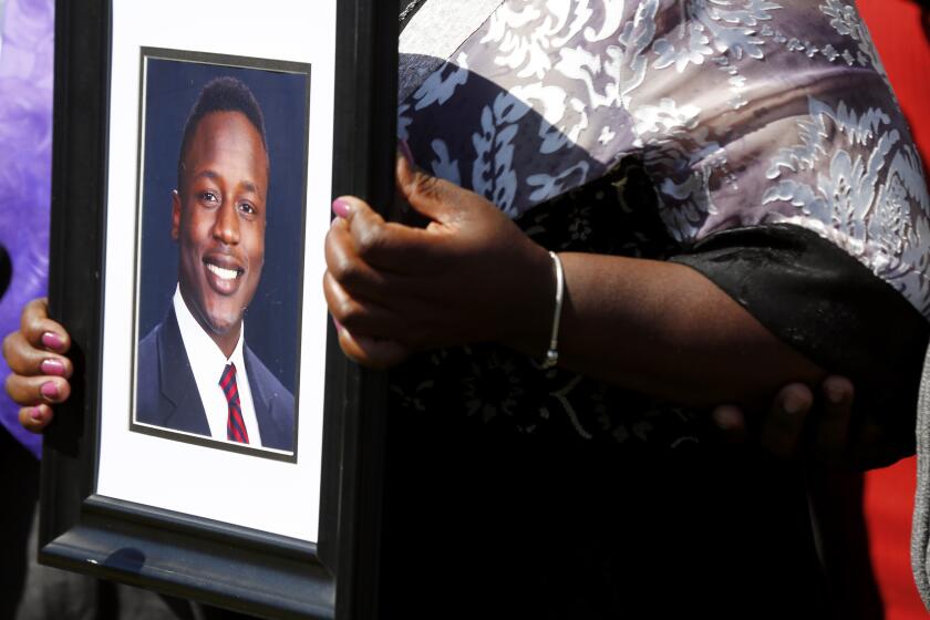 FILE - Caroline Ouko, mother of Irvo Otieno, holds a portrait of her son at the Dinwiddie Courthouse, March 16, 2023, in Dinwiddie, Va. Second-degree murder charges against two sheriff’s deputies and a hospital worker have been reduced to involuntary manslaughter in the death of Otieno, a Virginia man who was pinned to the floor for about 11 minutes while being admitted to a state psychiatric hospital. (Daniel Sangjib Min/Richmond Times-Dispatch via AP, File)