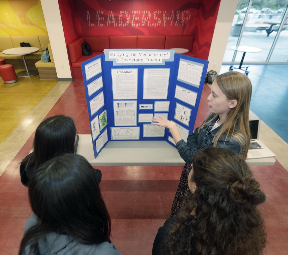 Jordan Lay, right, discusses her work with science partner Artis Phillips (on left in front), "Studying the Mechanism of Chaperone Protein" Friday at the LCHS annual science fair. The team placed second.