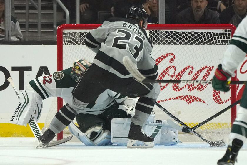 Los Angeles Kings right wing Dustin Brown, right, scores on Minnesota Wild goaltender Alex Stalock during the third period of an NHL hockey game Saturday, March 7, 2020, in Los Angeles. (AP Photo/Mark J. Terrill)