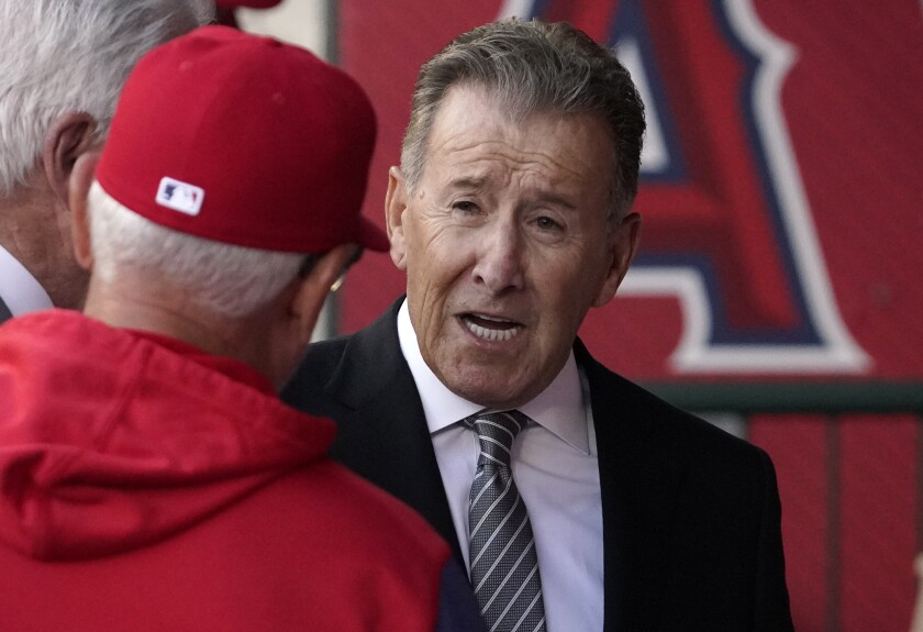 Angels owner Arte Moreno talks with former Angels manager Joe Maddon in the dugout.