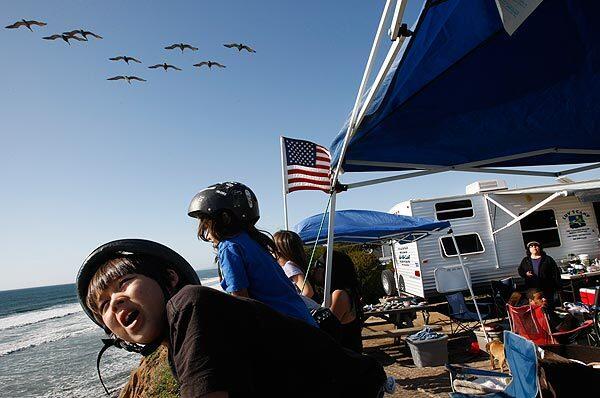 Ryan Santos, 8, watches pelicans glide over his oceanfront campsite at South Carlsbad State Beach. His family is spending five nights in a trailer they rented from Luv 2 Camp Rentals, a state park-sanctioned concession operator that delivers the ready-to-use camp trailers to the park. The state park system gets a percentage of the rental fee as part of a plan to generate more revenue from the parkland.