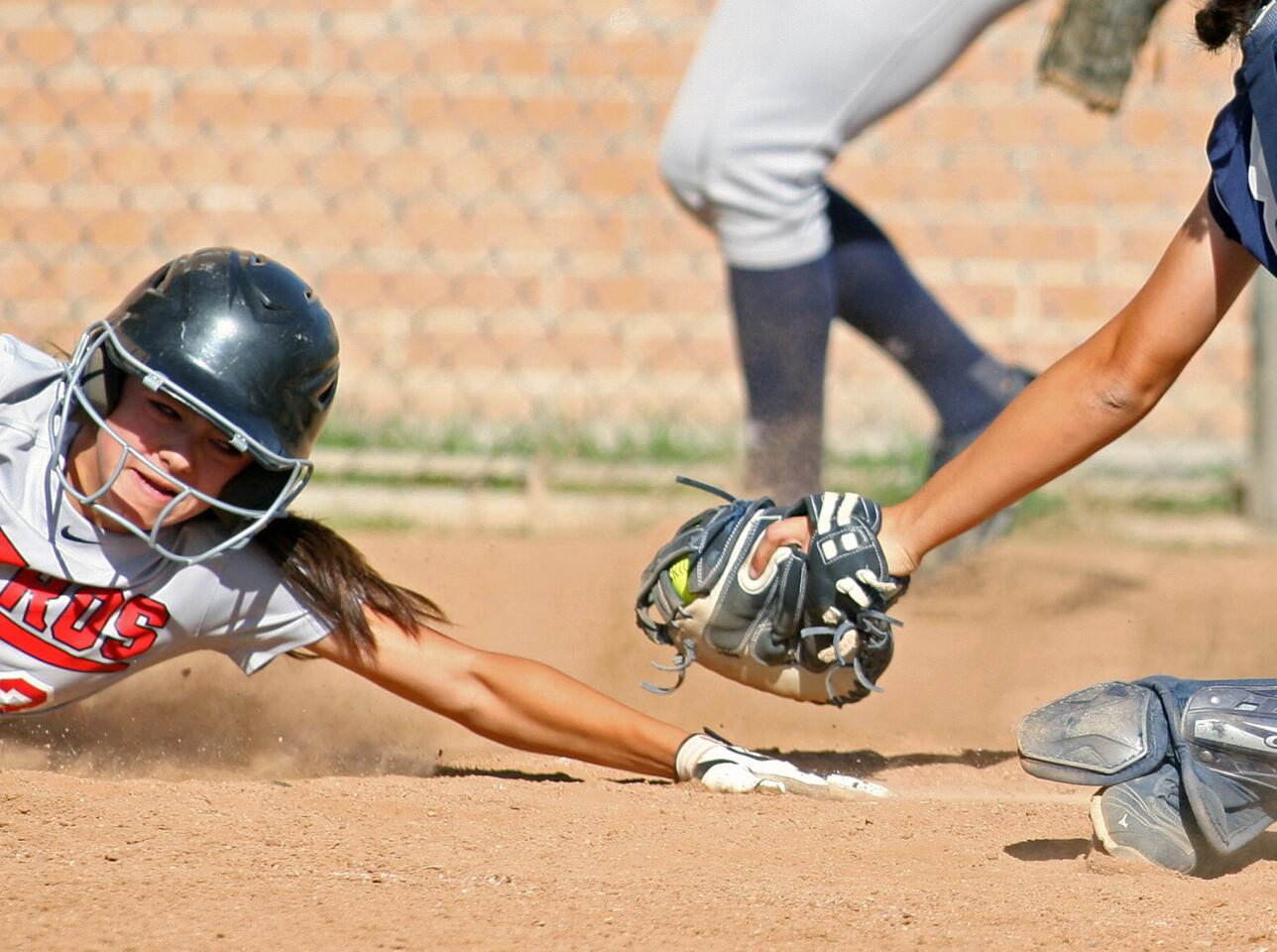 Glendale's Sammy Fabian reaches to make sure she is safely touching home plate to score against Crescenta Valley in a Pacific League softball game at Glendale High School on Thursday, May 1, 2014.