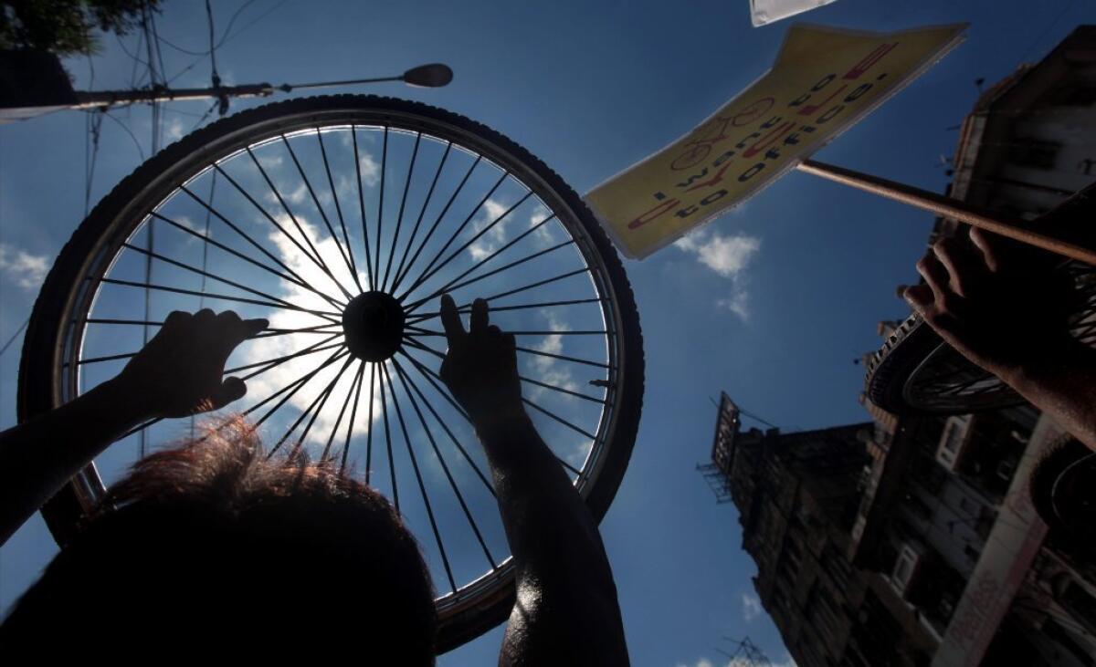Bicyclists in Calcutta hold up a spoked wheel in a Wednesday protest against the city's ban on riding bikes on 174 city thoroughfares.
