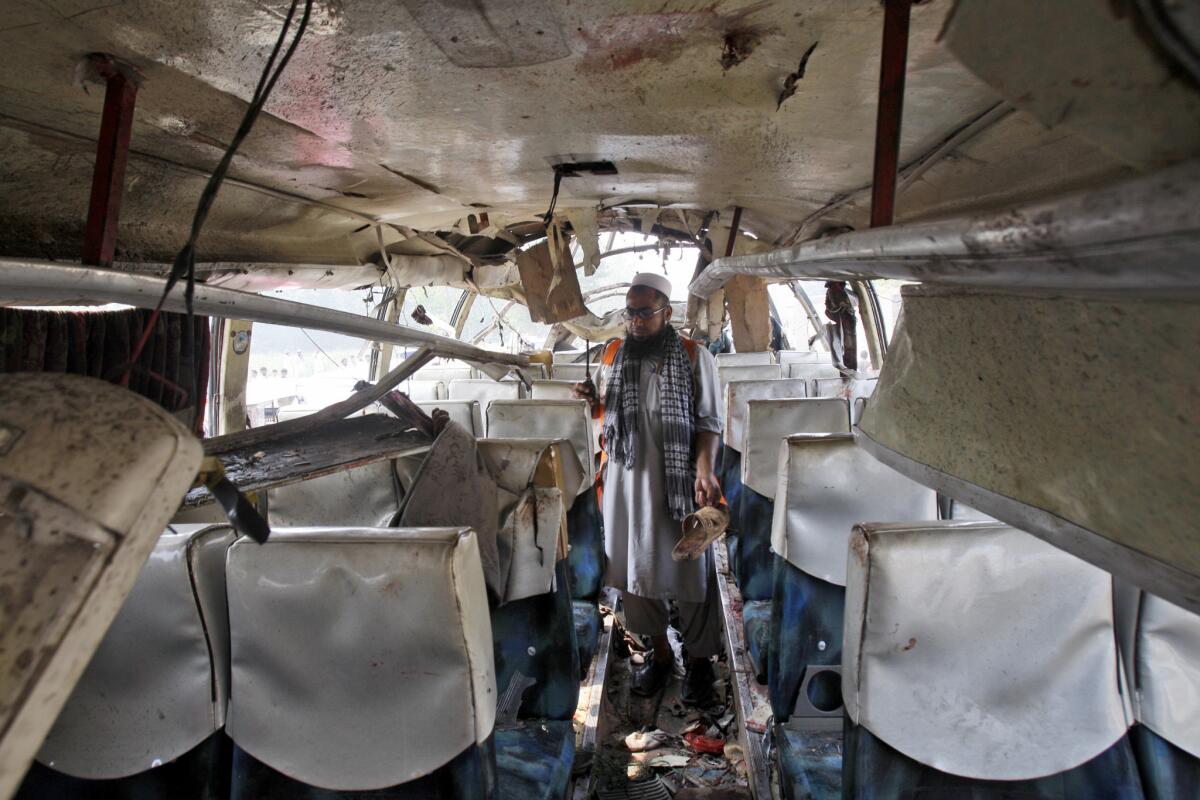 A Pakistani official collects evidence from the wreckage of a bus destroyed in a bomb blast in Peshawar on Friday.