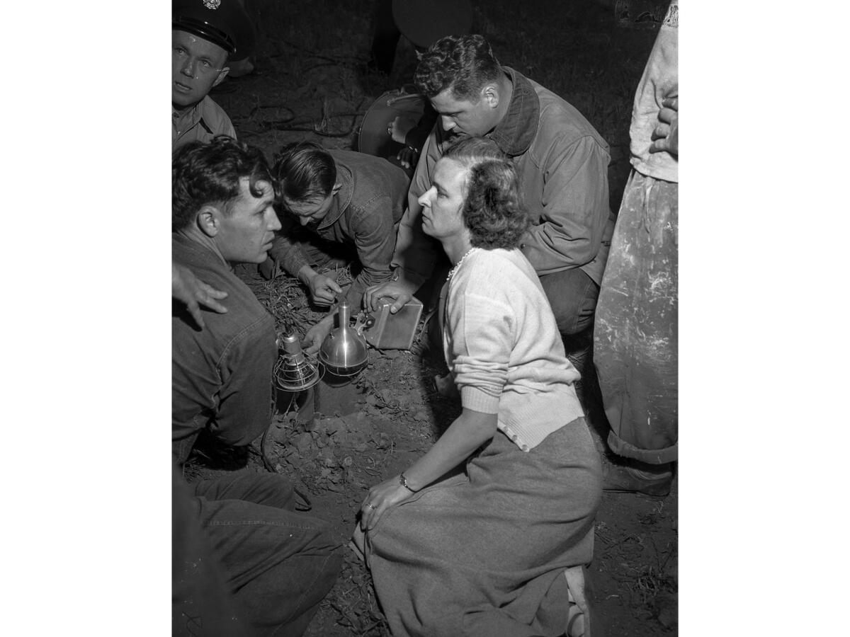 April 8, 1949: Mrs. Hamilton Lyon Jr. of Chula Vista waits during the rescue operation for niece Kathy Fiscus 3, trapped in 14-inch-wide water pipe. Firefighters hold lights over the rim of the pipe.