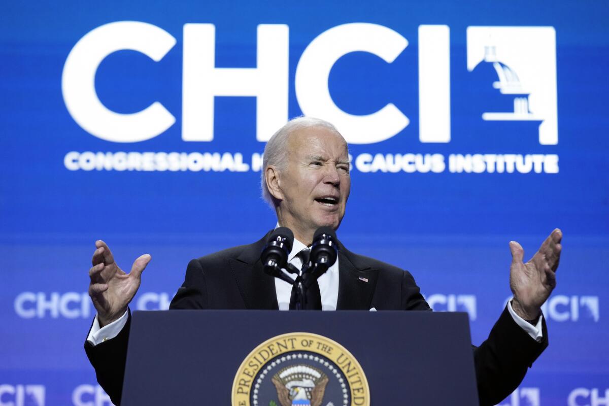 President Biden speaks before backdrop with the letters "CHCI" and a logo.
