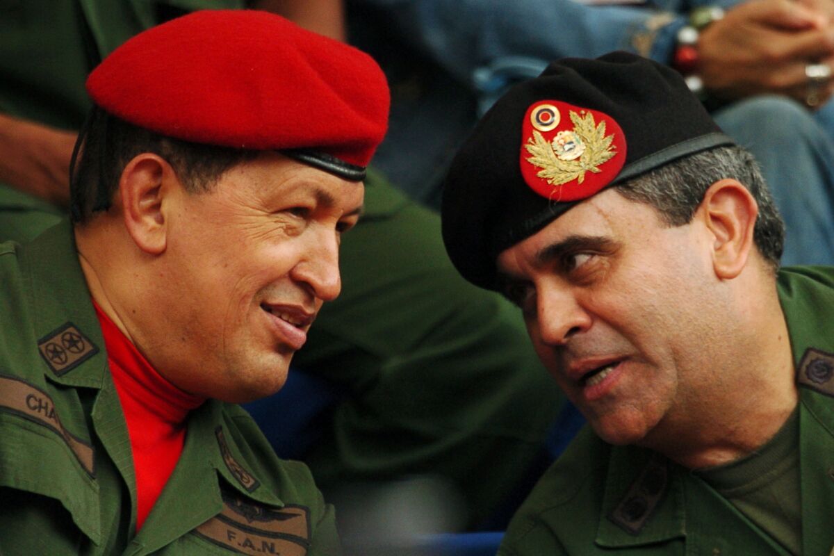 FILE - In this Aug. 11, 2006 file photo, Venezuela's President Hugo Chavez, left, and his Defense Minister Raul Baduel attend the military reserve changing of command ceremony in Caracas, Venezuela, The former Defense Minister has died on Oct. 12, 2021, after contracting COVID-19 inside the prison where he was being held, accused of plotting a coup against Venezuelan President Nicolas Maduro. (AP Photo/Gregorio Marrero, File)