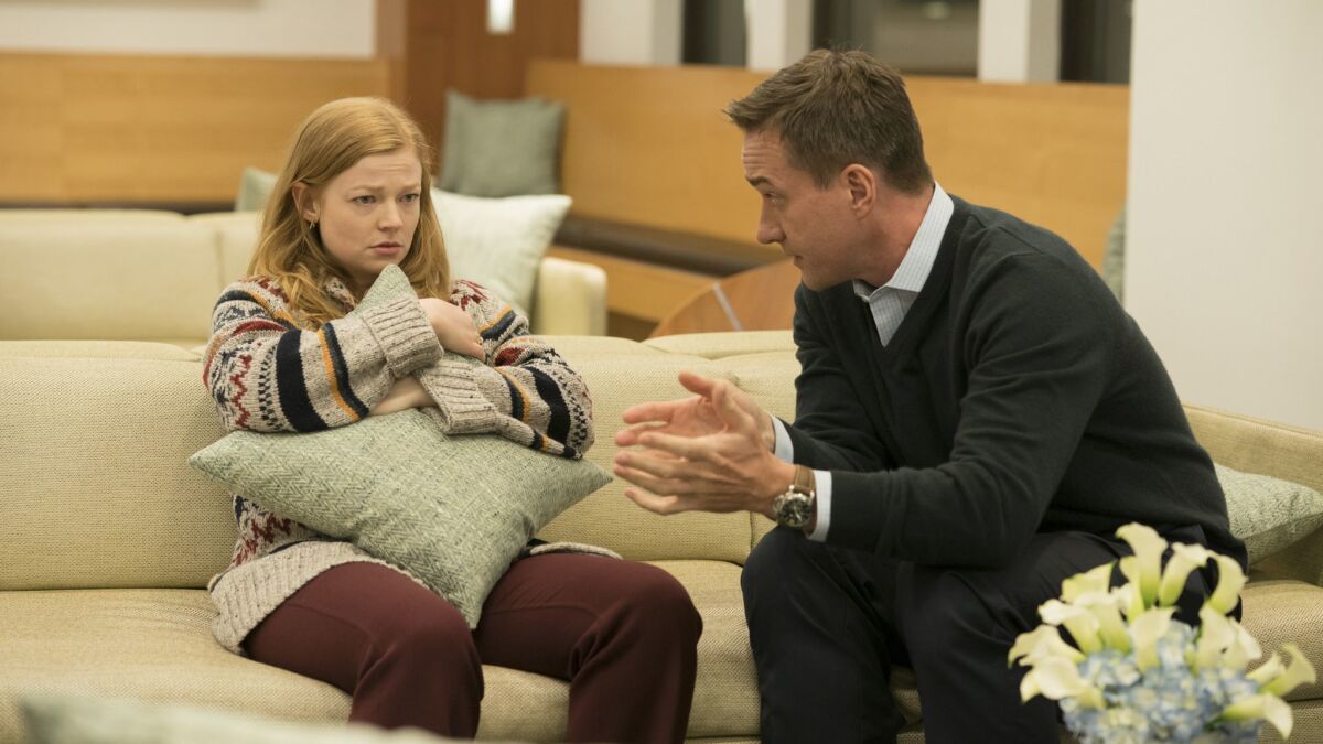 Sarah Snook, holding a throw pillow, and Matthew Macfadyen on a couch in "Succession."