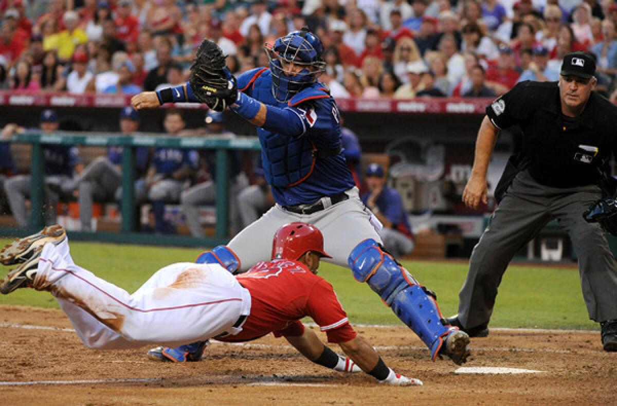 Angels third baseman Luis Jimenez dives toward home plate to score in the second inning ahead of a tag by Rangers catcher A.J. Pierzynski on Saturday night in Anaheim.
