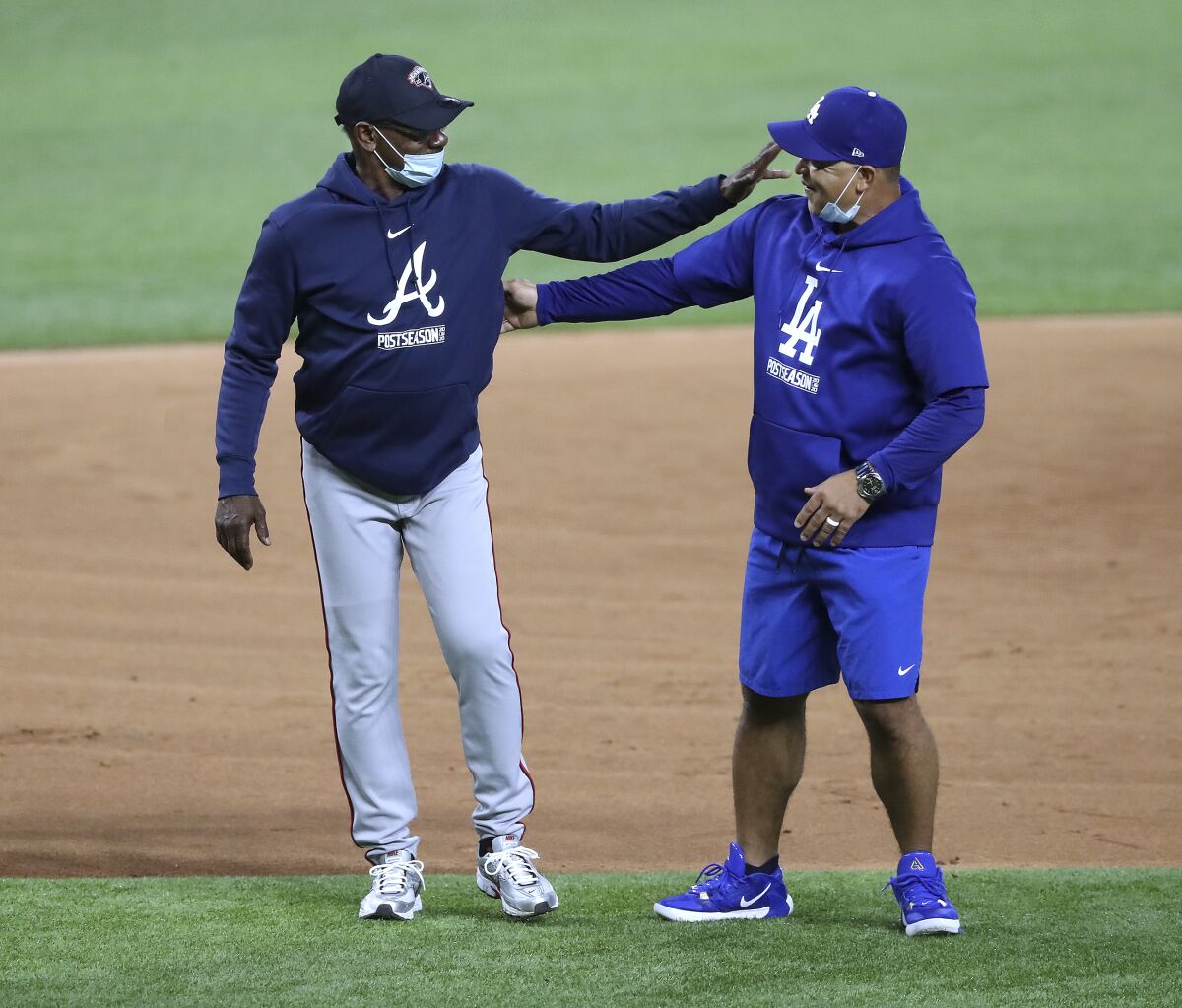 Atlanta Braves third base coach Ron Washington, left, and Los Angeles Dodgers manager Dave Roberts greet each other during team baseball workouts the day before facing in the best-of-seven National League Championship Series at Globe Life Field, Sunday, Oct. 11, 2020, in Arlington. (Curtis Compton/Atlanta Journal-Constitution via AP)