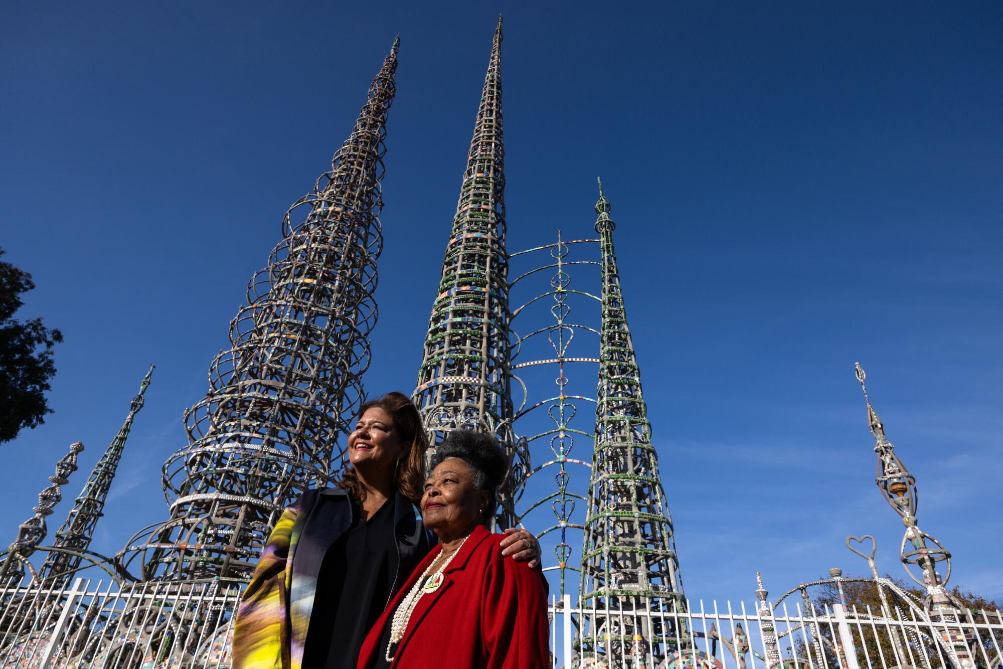 Elizabeth Alexander puts her arm around Rosie Lee Hooks before the mosaic-covered forms of the Watts Towers